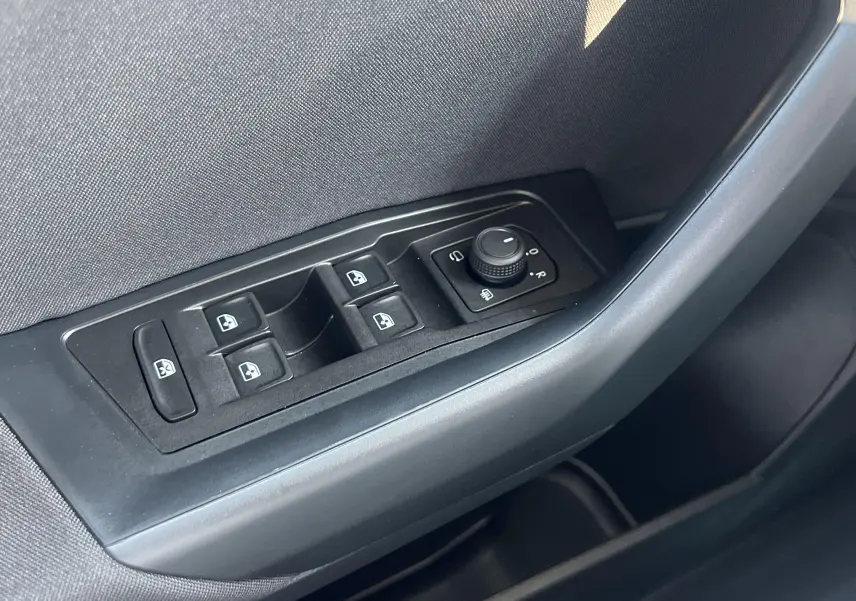 Commande des vitres électriques et réglage des rétroviseurs sur la portière côté gauche d'un Volkswagen T-Roc gris Indium.