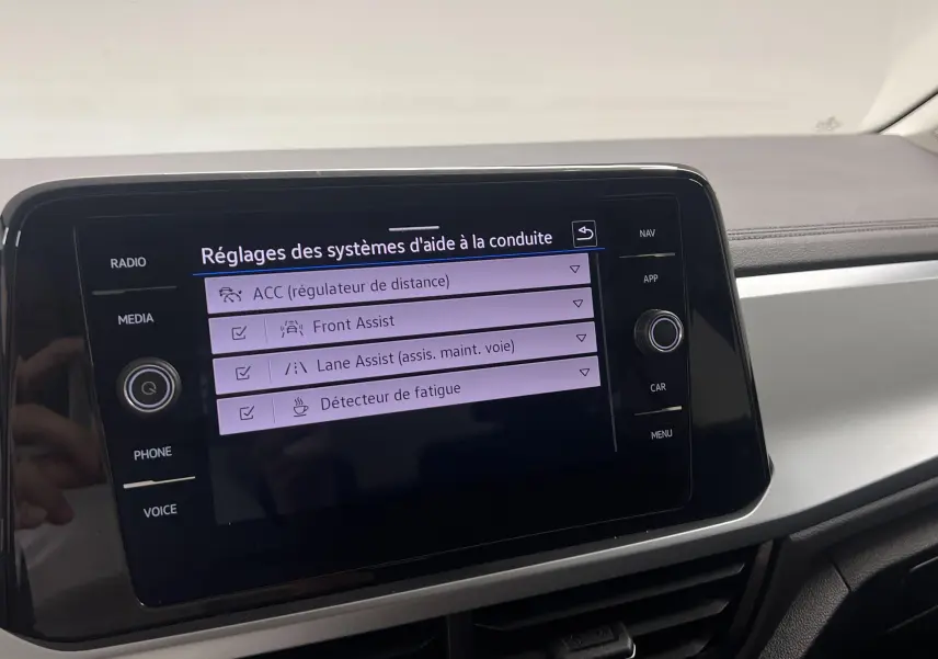Écran central tactile du Volkswagen T-Roc 2024 affichant les réglages des aides à la conduite dans un intérieur gris clair.