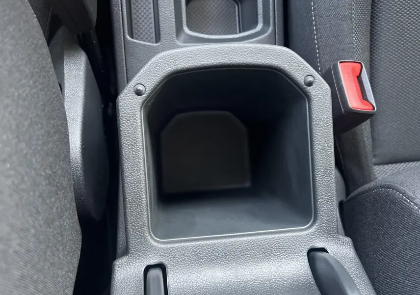 Gros plan sur le rangement central noir entre les sièges avant du Volkswagen T-Roc 2024 gris Indium.