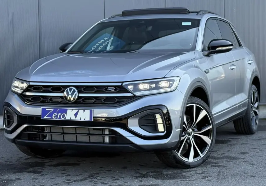 Volkswagen T-Roc gris pyrite en 3/4 avant droit avec jantes alliage 19 pouces et toit ouvrant visible.