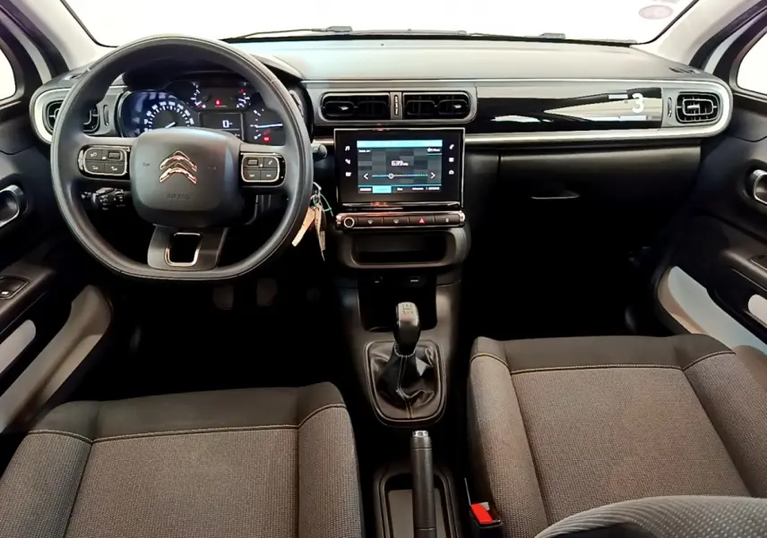 Intérieur de la Citroën C3 PureTech 82 blanc, vue frontale du tableau de bord avec écran tactile et volant multifonctions.
