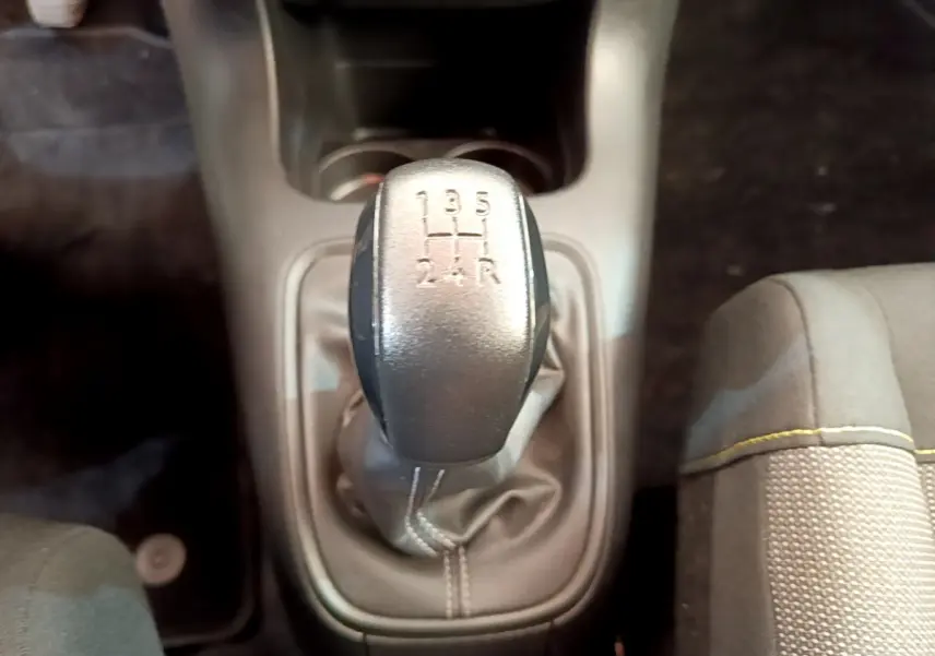 Le levier de vitesse manuel gris de la Citroën C3 PureTech 82 S&S, vu de dessus, avec siège tissu à couture jaune.