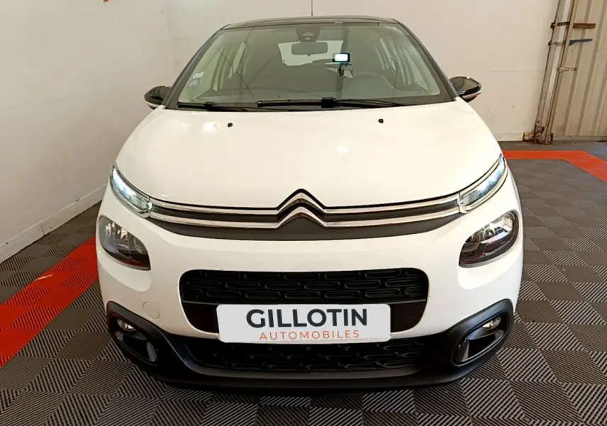 Vue frontale d'une Citroën C3 blanche de 2019 avec calandre noire et feux LED distinctifs dans un showroom.