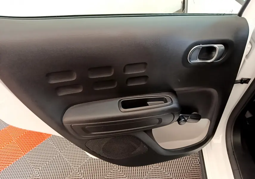 Vue rapprochée de la porte avant gauche noire et blanche d'une Citroën C3 PureTech 2019 avec poignée chromée.