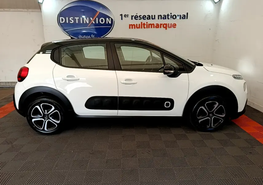 Profil droit d'une Citroën C3 PureTech 82 blanc avec toit noir et protections latérales noires distinctives.