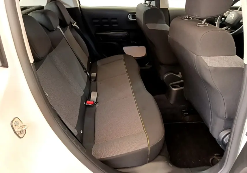 Vue intérieure côté gauche montrant la banquette arrière noire et grise de la Citroën C3 blanche de 2019.