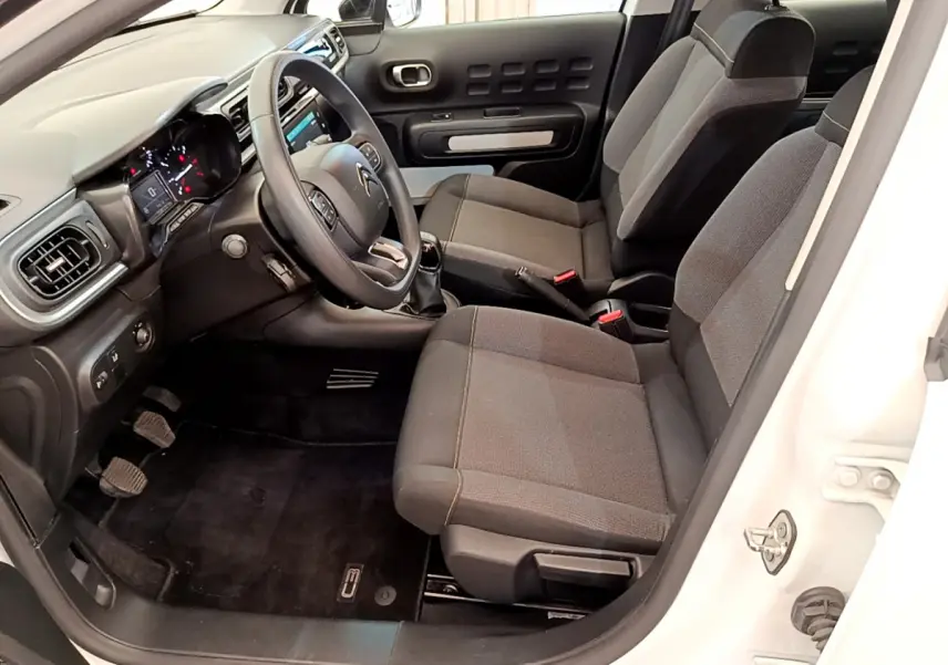 Intérieur côté conducteur de la Citroën C3 blanche 2019, montrant sièges gris et tableau de bord avec écran tactile.