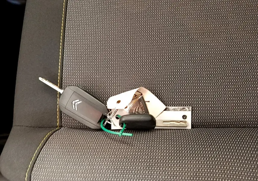 Clé de voiture Citroën posée sur un siège tissu gris avec surpiqûres jaunes, intérieur d'une C3 blanche 2019.