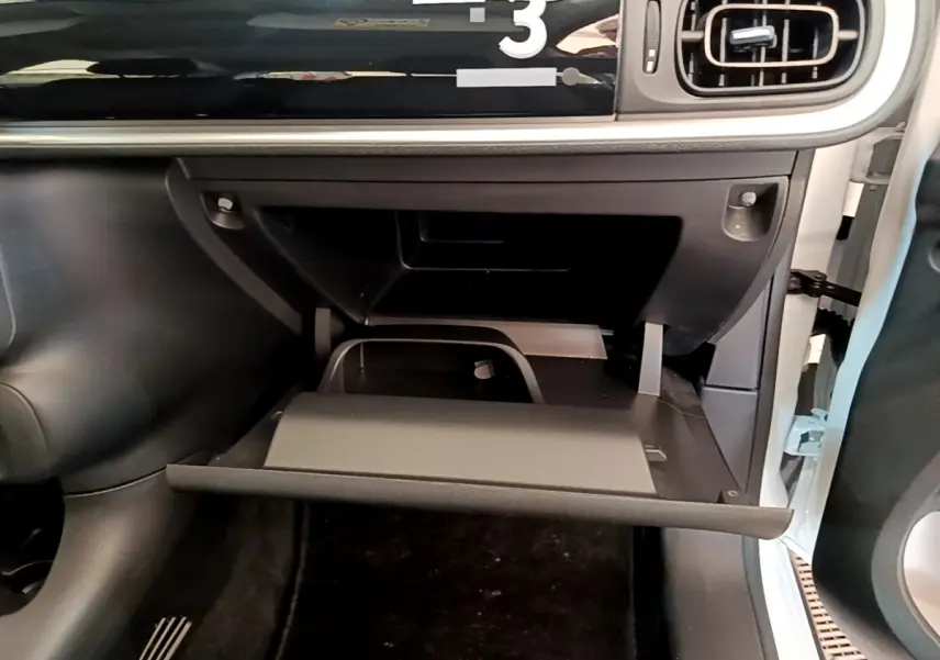 Gros plan sur la boîte à gants ouverte côté passager d'une Citroën C3 blanche, tableau de bord noir visible.