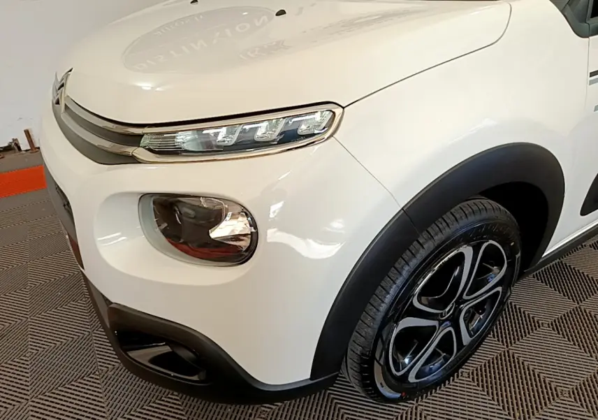 Gros plan sur l'avant droit blanc de la Citroën C3 2019 avec phares LED et jante noire à motifs distinctifs.