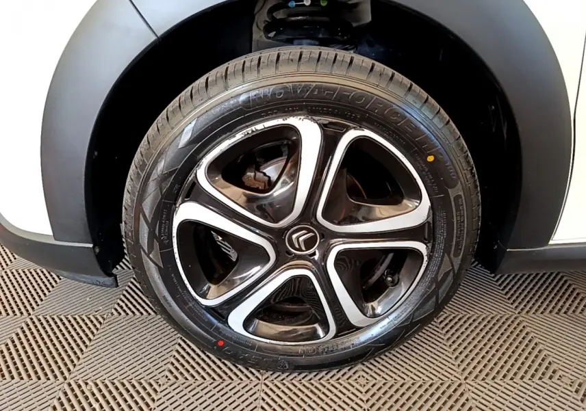 Gros plan sur la roue arrière droite d'une Citroën C3 blanche avec passage de roue noir mat et jante en alliage.