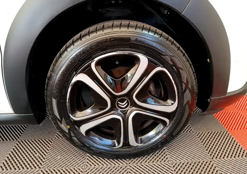 Gros plan sur la roue avant droite noire et chromée de la Citroën C3 blanche 2019 PureTech Graphic