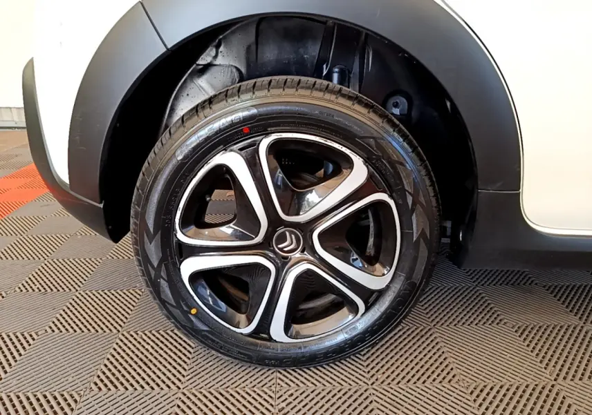 Gros plan sur la roue avant droite de la Citroën C3 blanche, mettant en valeur la jante noire et argentée au design moderne.