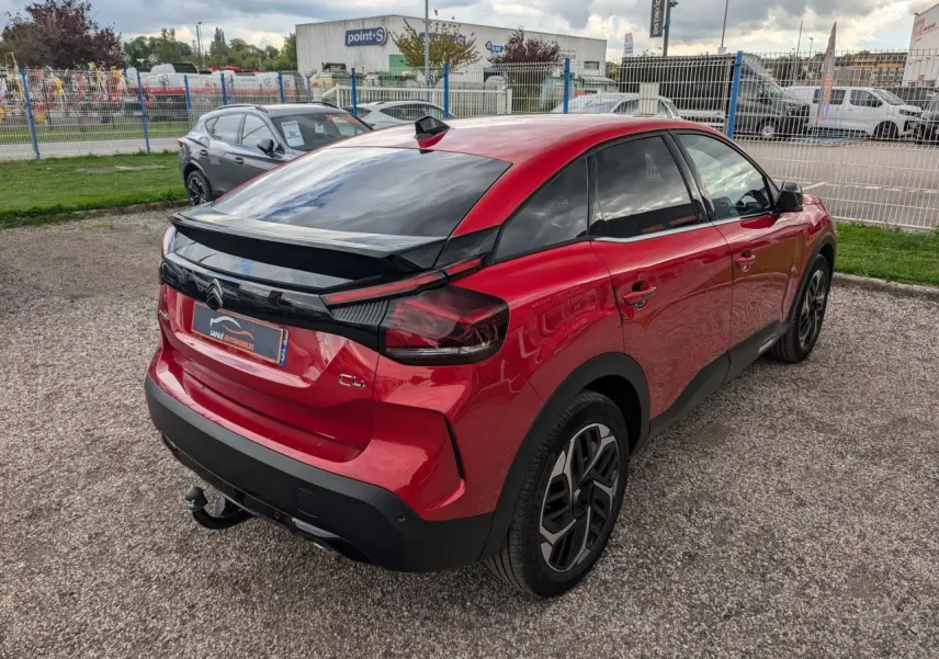 Vue 3/4 arrière droite de la Citroën C4 2024 rouge foncé avec attelage col de cygne et jantes alliage 18 pouces.
