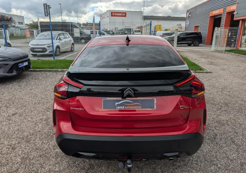 Vue arrière d'une Citroën C4 rouge foncé 2024 avec attelage col de cygne et lunette arrière surteintée.