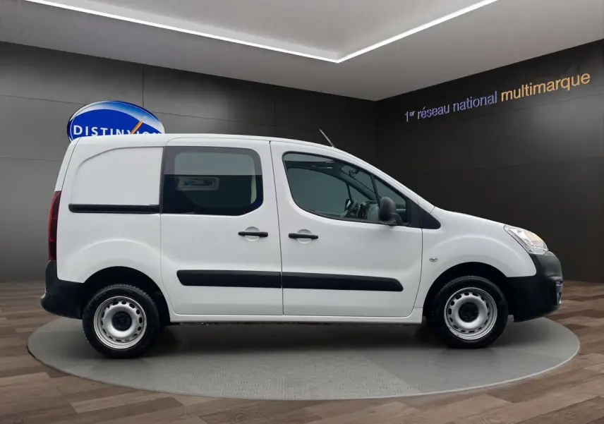 Vue de profil côté droit du Citroën Berlingo blanc 2018 version Van M BlueHDi avec protections noires sur fond intérieur showroom.