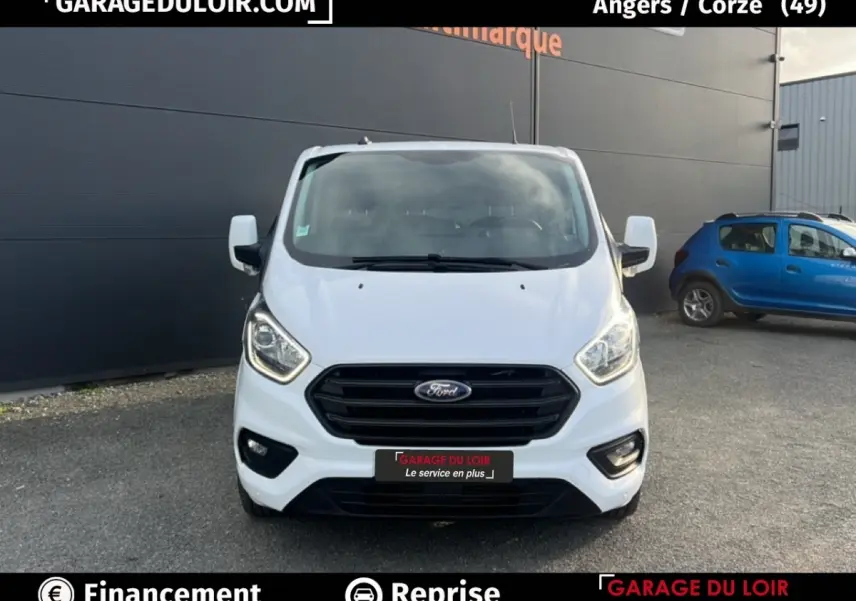 Vue frontale du Ford Transit Custom fourgon blanc 2023 avec calandre noire et feux LED allumés.