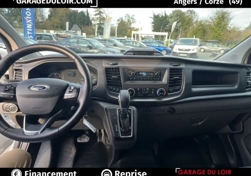 Intérieur du Ford Transit Custom blanc 2023, vue du poste de conduite avec volant multifonction et tableau de bord complet.