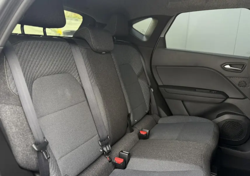 Vue intérieure côté droit des sièges arrière gris foncé du Renault Captur 2026 avec ceinture de sécurité et garnitures tissu.