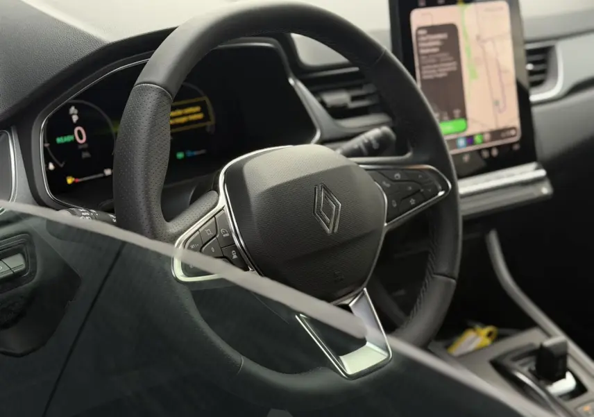Vue rapprochée du volant noir textile du Renault Captur 2026 avec tableau de bord numérique et écran tactile central.