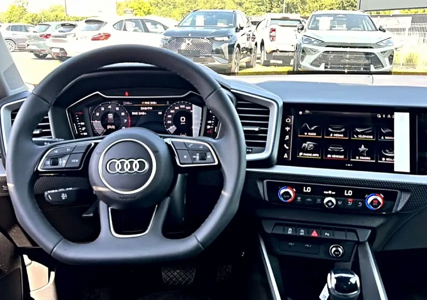 Vue intérieure centrée sur le volant multifonction et l’écran tactile du tableau de bord de l’Audi A1 Sportback 2026.