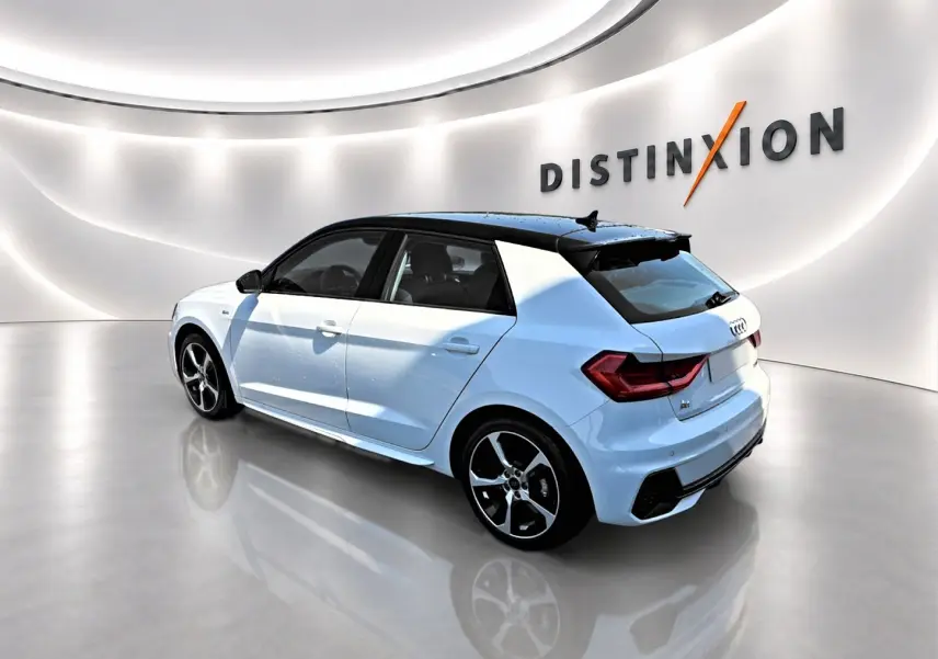 Audi A1 Sportback blanc et noir vue 3/4 arrière droit, avec jantes alu et toit contrasté noir dans showroom lumineux.