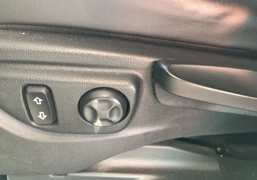 Gros plan sur les commandes de réglage électrique du siège avant gauche d'un Opel Mokka blanc de 2015.