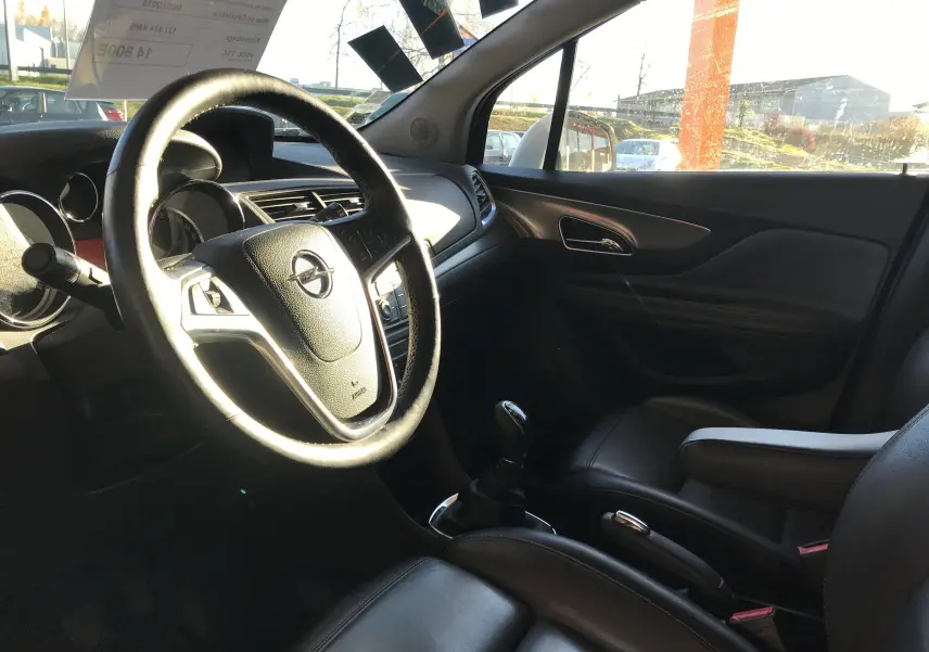 Intérieur de l'Opel Mokka blanc vu côté conducteur, volant cuir, tableau de bord et sièges noirs en cuir.