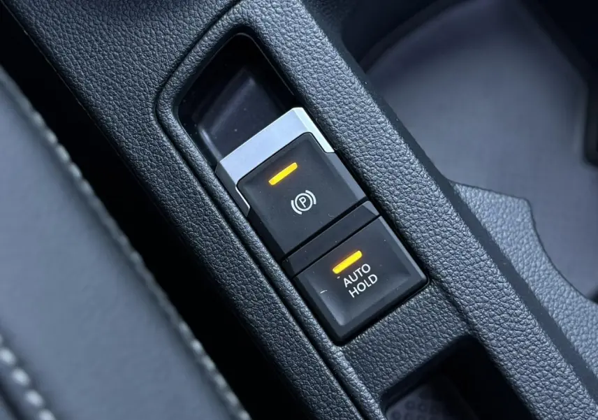 Gros plan sur les commandes du frein de stationnement électromécanique et Auto Hold du Volkswagen T-Roc gris Pyrite.