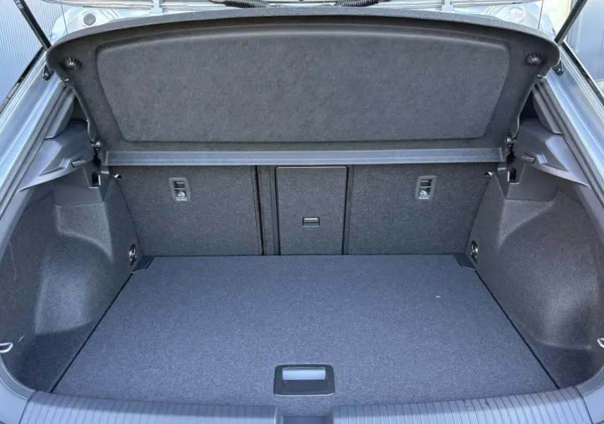Coffre ouvert vu de l'arrière du Volkswagen T-Roc gris Pyrite, montrant un espace de chargement propre et bien agencé.