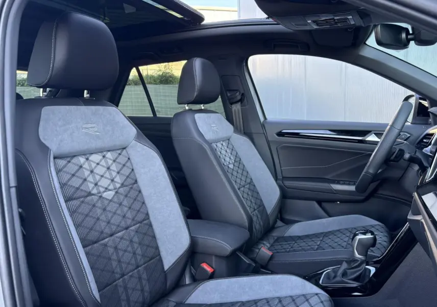 Vue intérieure côté conducteur du Volkswagen T-Roc R-Line 2025, sièges bicolores gris et noir avec logo R brodé.