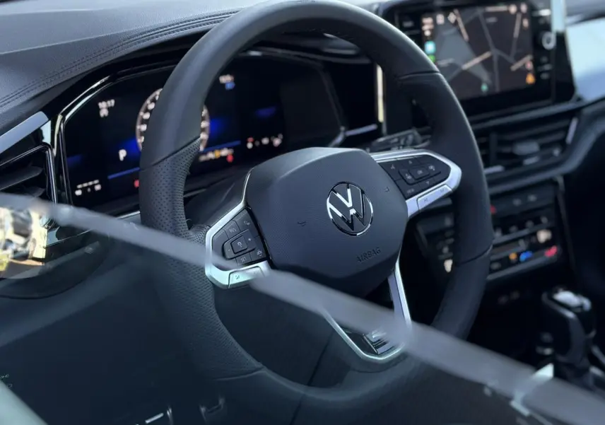 Volant multifonction noir avec logo Volkswagen au centre, tableau de bord digital et écran tactile du Volkswagen T-Roc 2025.