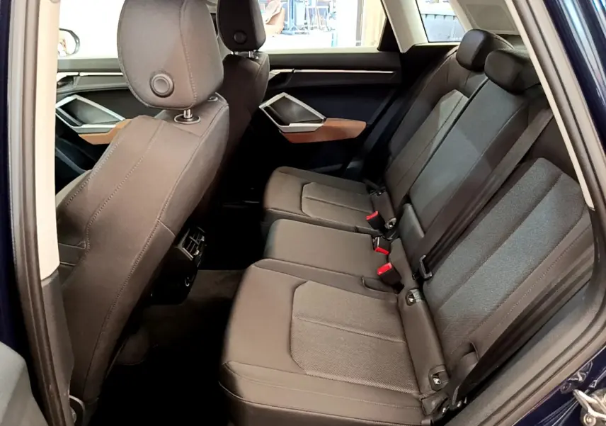 Vue intérieure côté droit des sièges arrière noirs d'un Audi Q3 35 TDI bleu, avec appuie-têtes et ceintures visibles.