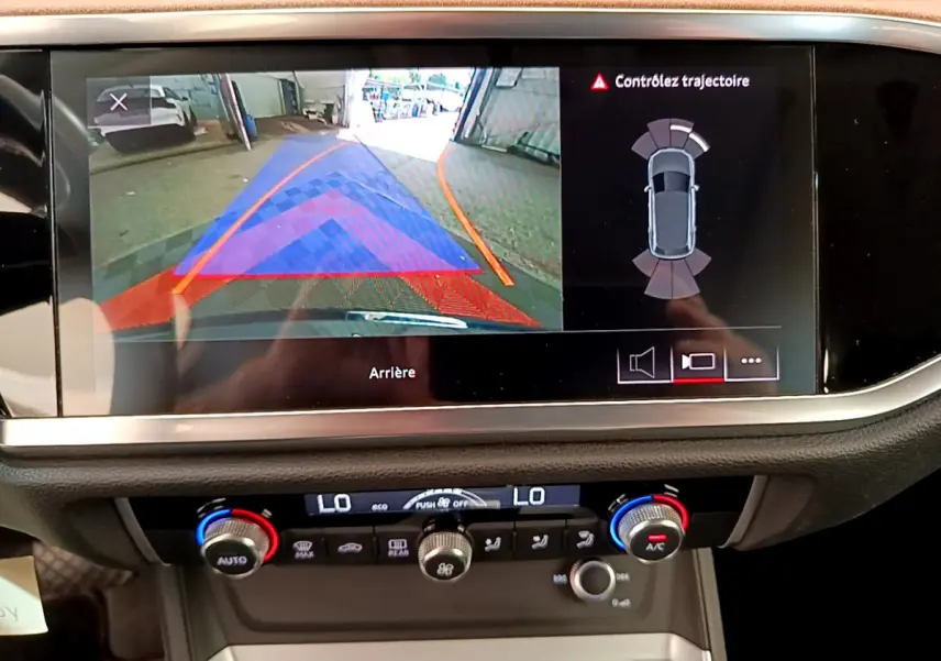 Écran multimédia affichant la caméra de recul et l'aide au stationnement d'un Audi Q3 bleu 2020, vue intérieure centrale.