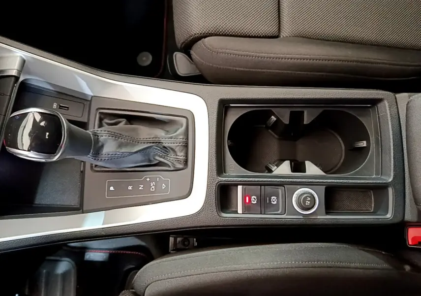 Vue plongeante sur la console centrale noire de l'Audi Q3 35 TDI 150 S tronic avec levier de vitesse et porte-gobelets.