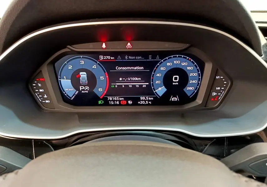 Vue rapprochée du tableau de bord numérique de l'Audi Q3 35 TDI 150 S Tronic Business Line avec affichage consommation et vitesse.
