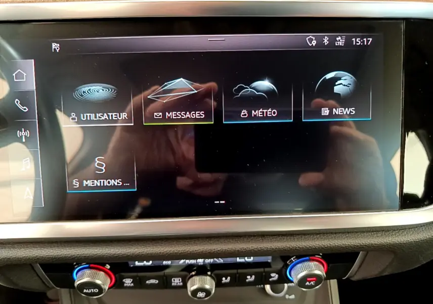 Écran tactile central affichant menu multimédia dans l’Audi Q3 bleu, vue rapprochée du tableau de bord intérieur.