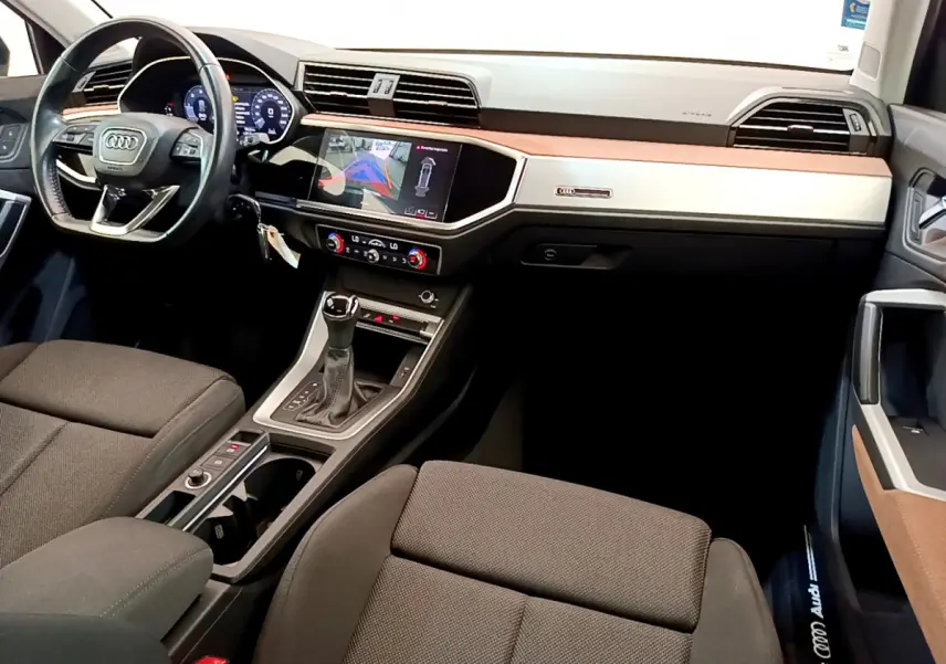 Intérieur Audi Q3 35 TDI 2020 vu de l'avant droit, tableau de bord noir et beige avec écran tactile et volant cuir noir.