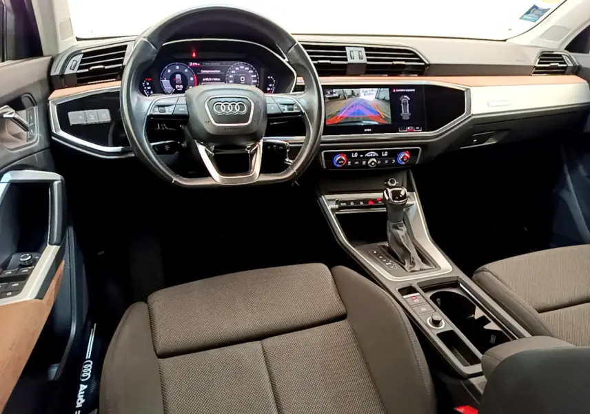 Vue intérieure avant de l'Audi Q3 35 TDI 2020, tableau de bord avec écran multimédia et volant cuir noir.