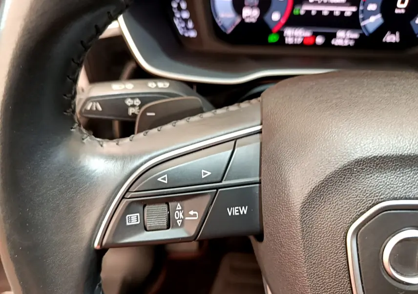 Gros plan sur les commandes gauche du volant cuir d’un Audi Q3 bleu 2020 avec tableau de bord numérique visible.