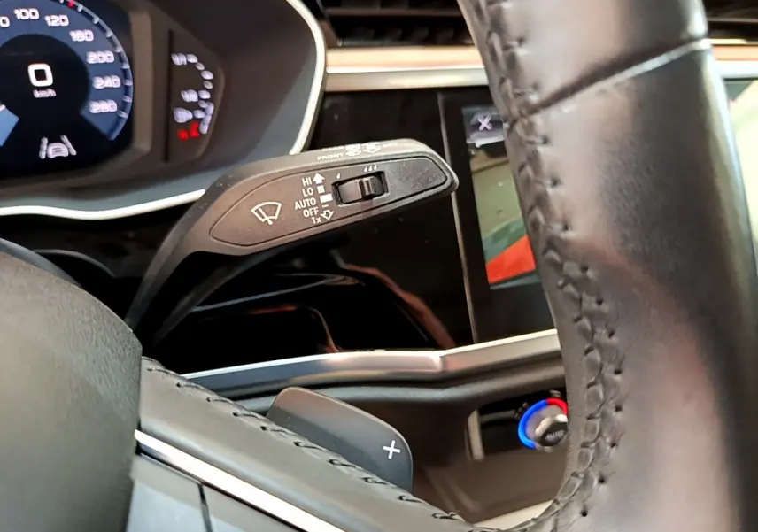 Gros plan sur le volant cuir et la manette d'essuie-glace du tableau de bord numérique d'un Audi Q3 bleu 2020