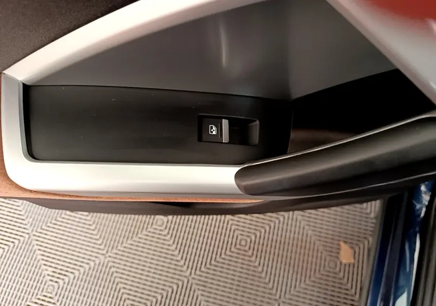 Bouton de verrouillage de porte sur la garniture intérieure côté gauche d'un Audi Q3 bleu, vue rapprochée.