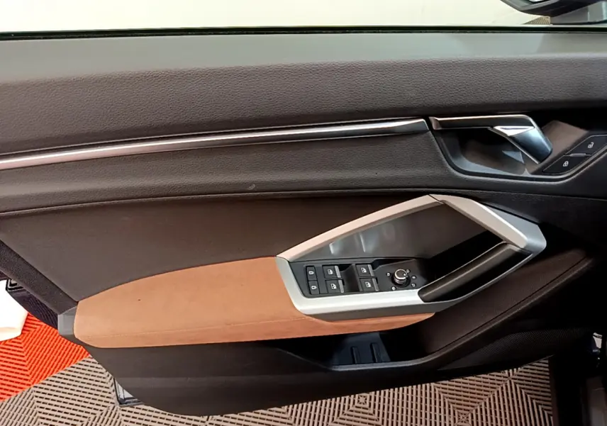 Détail de la porte côté conducteur de l'Audi Q3 35 TDI 150 S tronic Business Line 2020 avec garniture marron et commandes électriques.