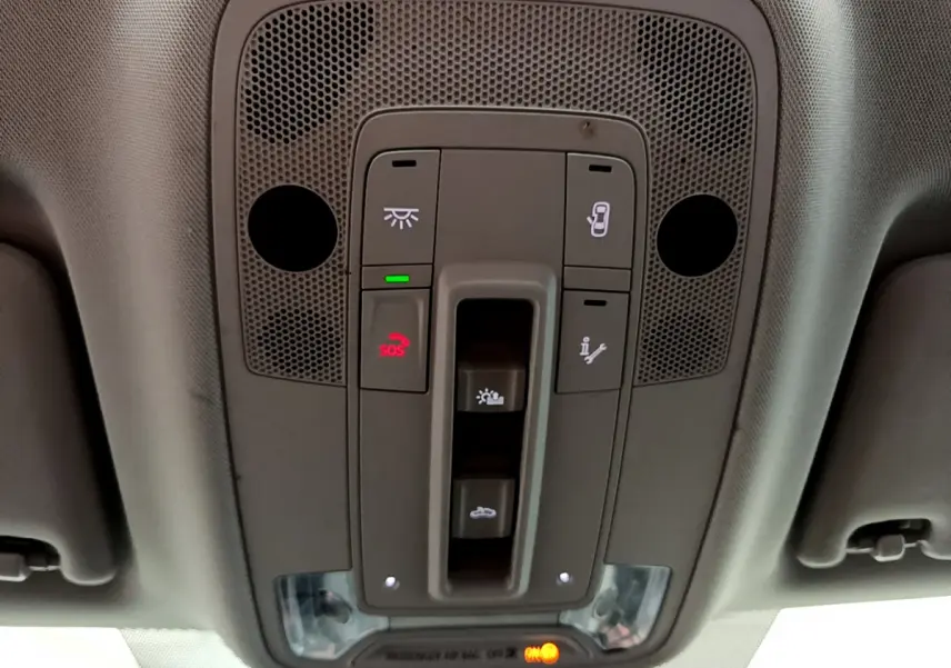 Vue en plongée sur le panneau de commandes de toit gris de l'Audi Q3 bleu, avec bouton SOS et éclairage intégré.