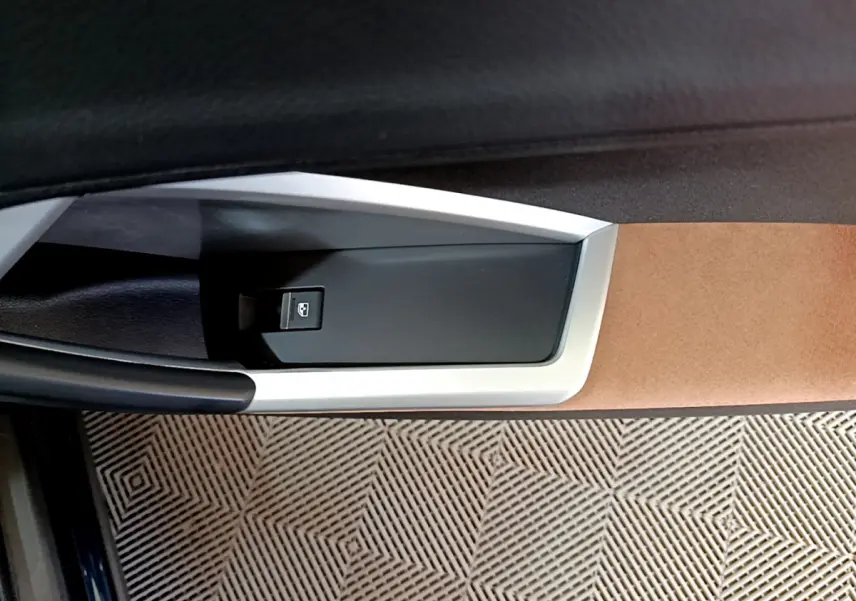 Détail de la commande de lève-vitre côté conducteur de l'Audi Q3 bleu, avec garniture beige et noire.