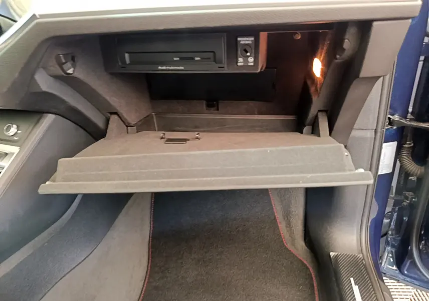 Vue intérieure côté passager de la boîte à gants ouverte d'un Audi Q3 bleu 35 TDI 2020 avec éclairage intérieur.