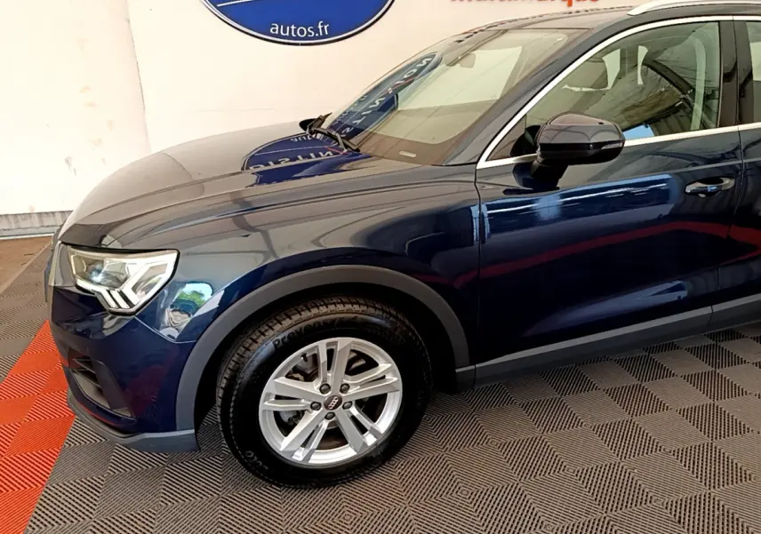 Vue de profil côté gauche d'un Audi Q3 bleu 2020 avec jante alliage et phares LED distinctifs.