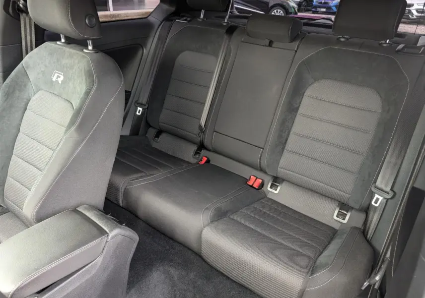 Vue intérieure des sièges arrière et avant gauche noirs de la Volkswagen Golf R 2017 avec logo "R" brodé sur l'appui-tête avant.