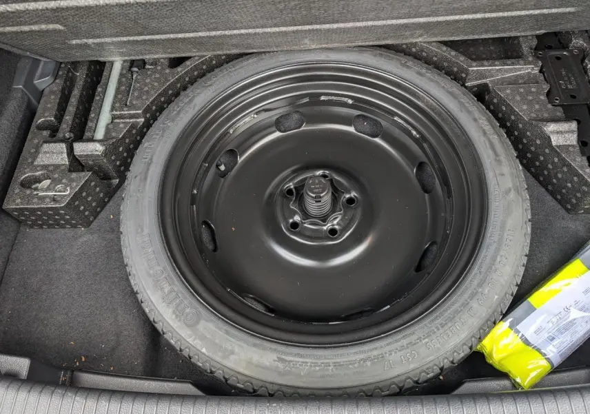 Roue de secours noire dans le coffre d'une Volkswagen Golf 2.0 TSI R 4Motion 2017, entourée d'accessoires de rangement.