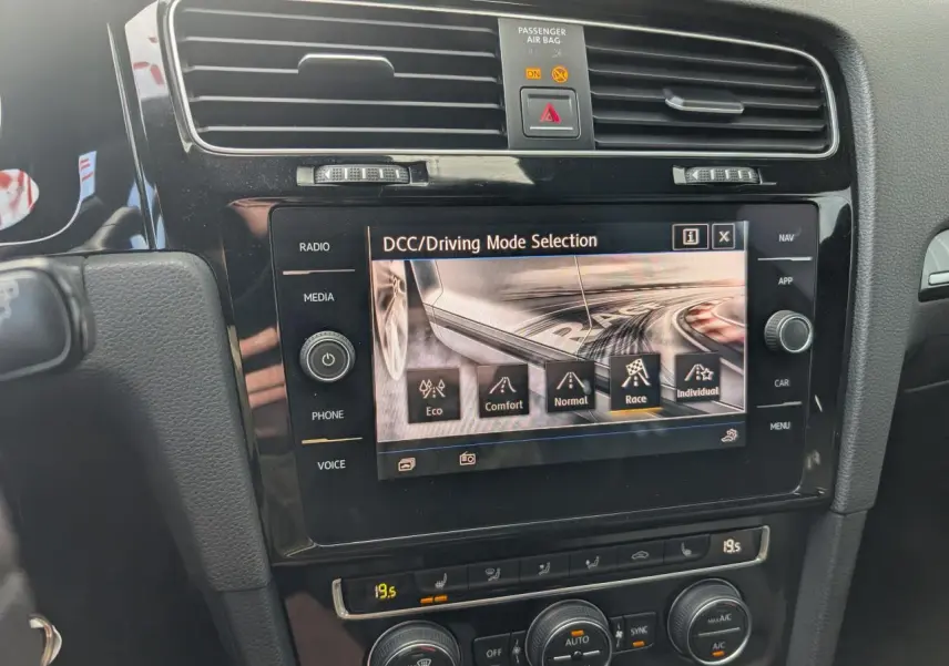 Vue rapprochée de la console centrale noire de la Volkswagen Golf R 2017, écran tactile affichant la sélection du mode de conduite DCC.